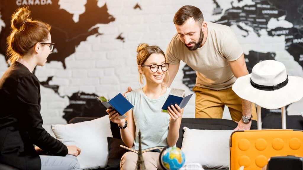 Happy couple reviewing passports and travel documents with an agent in a modern office, surrounded by travel essentials, representing a travel marketing agency helping plan global adventures.